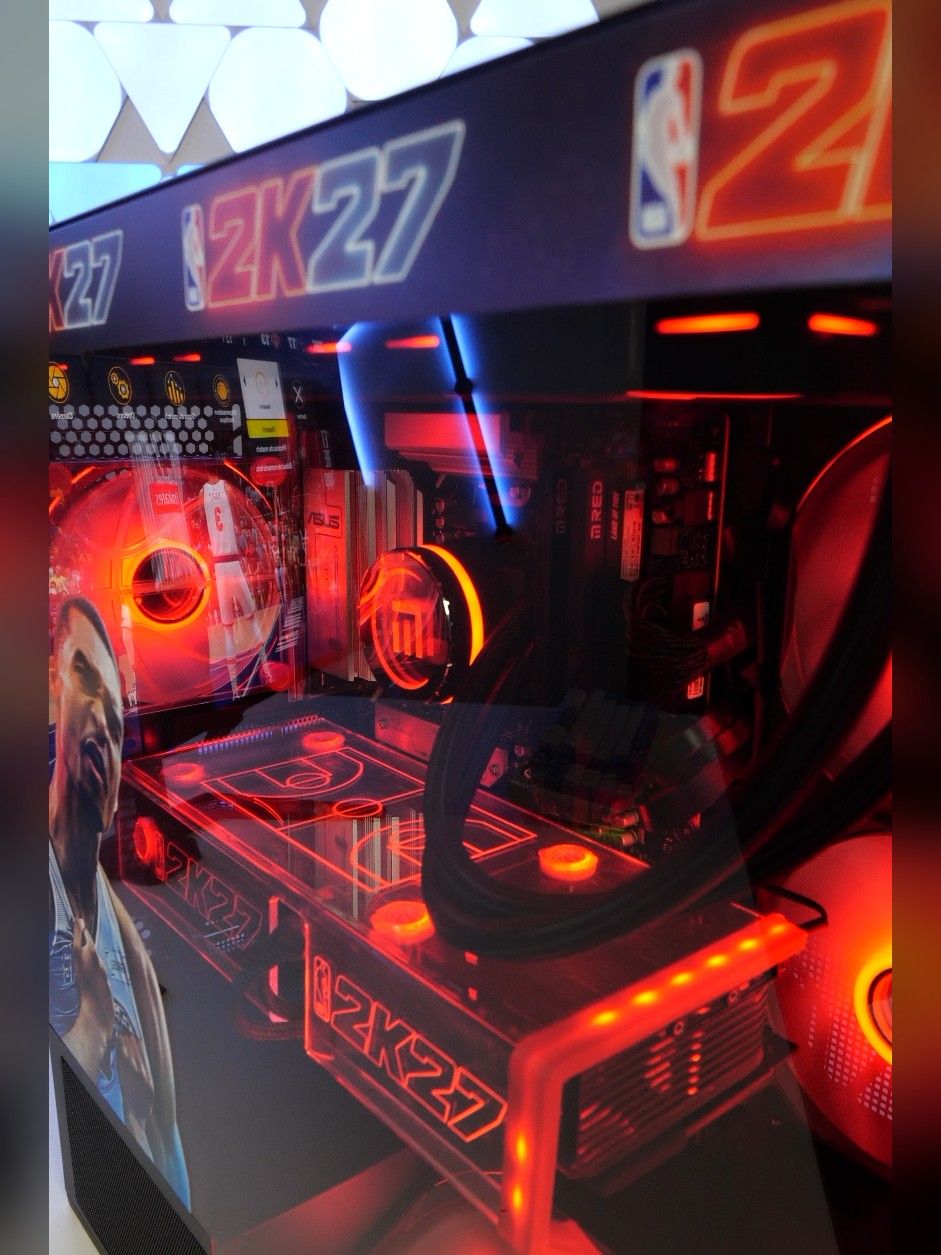 L’intérieur du boîtier vu de haut : carte mère ASUS, pompe au monogramme M.RED, tubes du watercooling et plaque gravée NBA 2K27