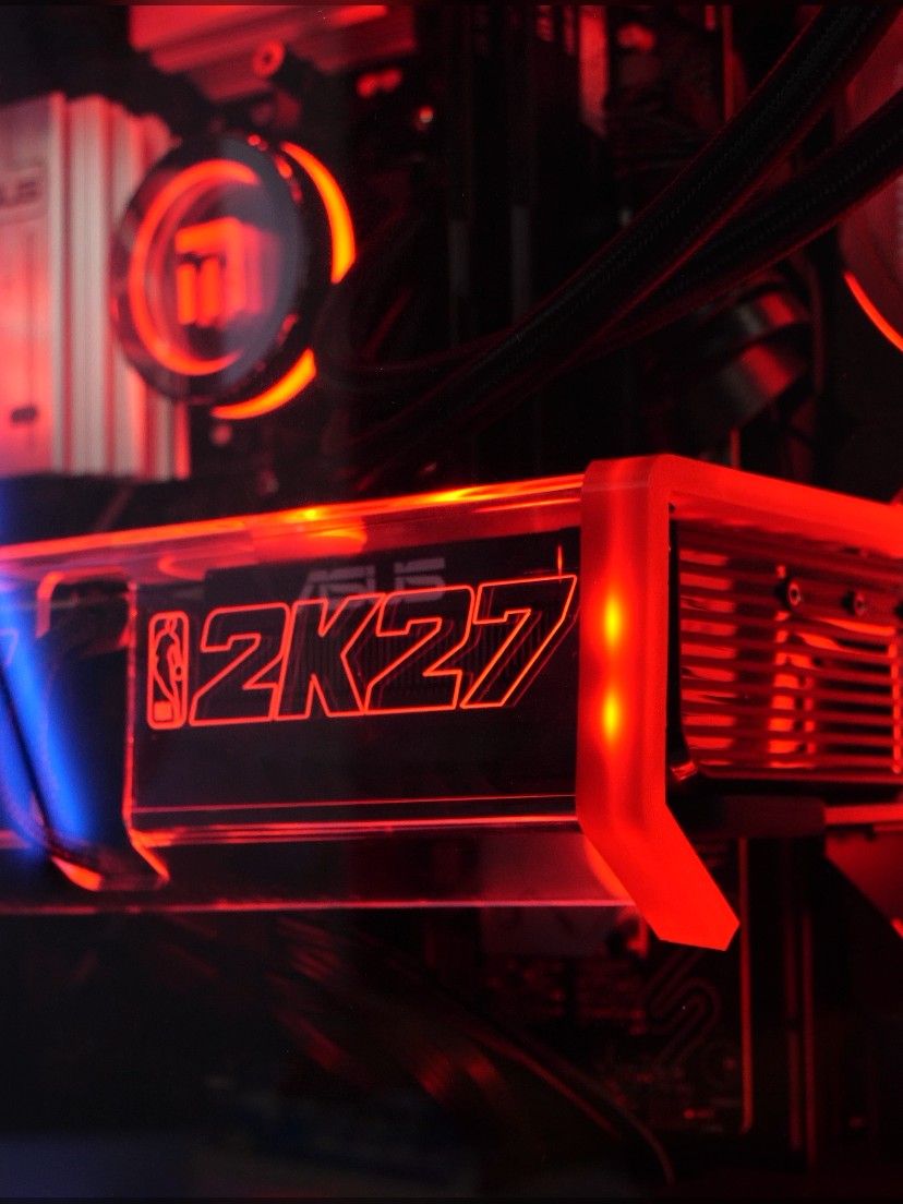 Le capot d’acrylique gravé NBA 2K27 posé sur la carte graphique ASUS, éclairé en rouge sous la pompe M.RED