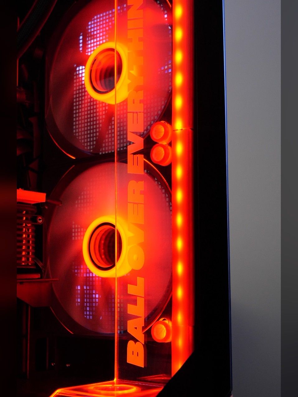 « Ball over everything » gravé à la verticale dans la tranche de verre, devant deux ventilateurs rouges et un bandeau de LED
